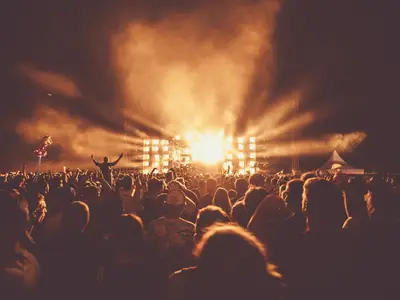 Concert crowd facing a brightly lit festival stage