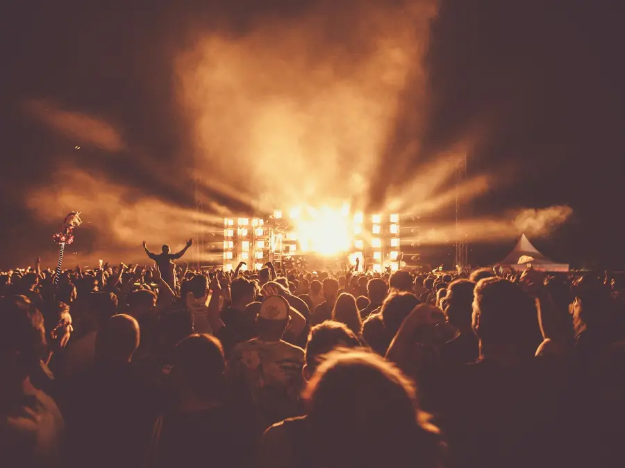 Concert crowd facing a brightly lit festival stage